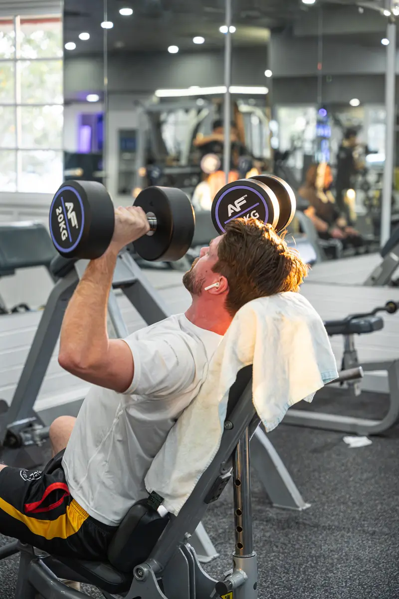 A member pressing dumbbells on a bench